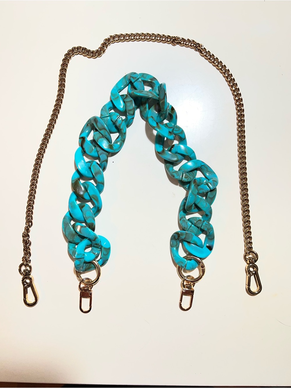 Two purse straps one I. Gold tone chain and one in faux turquoise colored links.